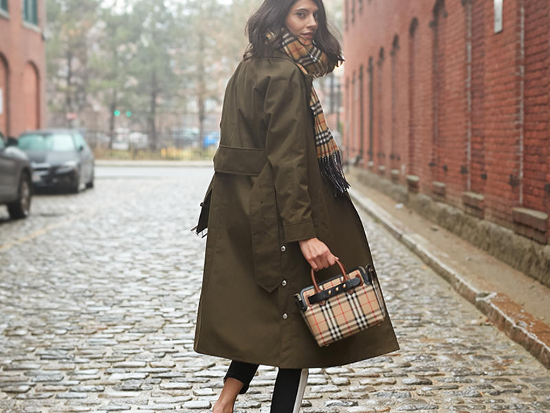 a person in a long coat and scarf walking down a street